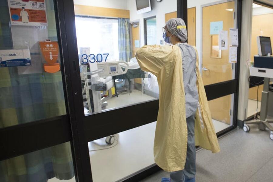  nurse puts on personal protective equipment before entering a patient’s room in a COVID-19 intensive care unit. THE CANADIAN PRESS/Jonathan Hayward