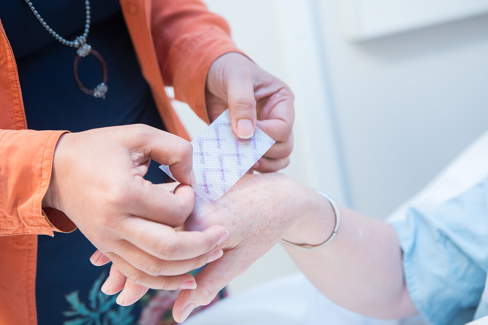 Female physician applies a wound care dressing to a patient's hand